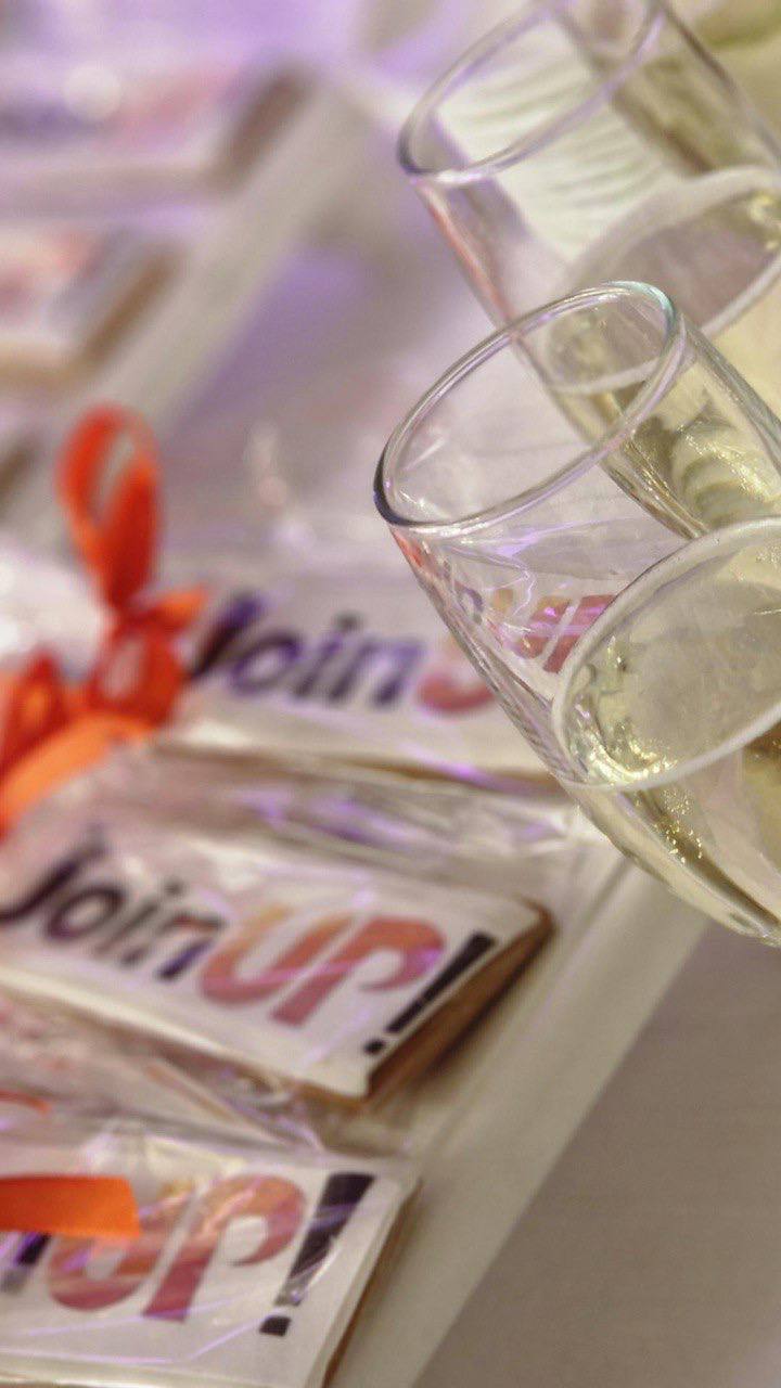 Бокалы с игристым напитком и брендированные пряники Join UP! на презентационном столе во время мероприятия