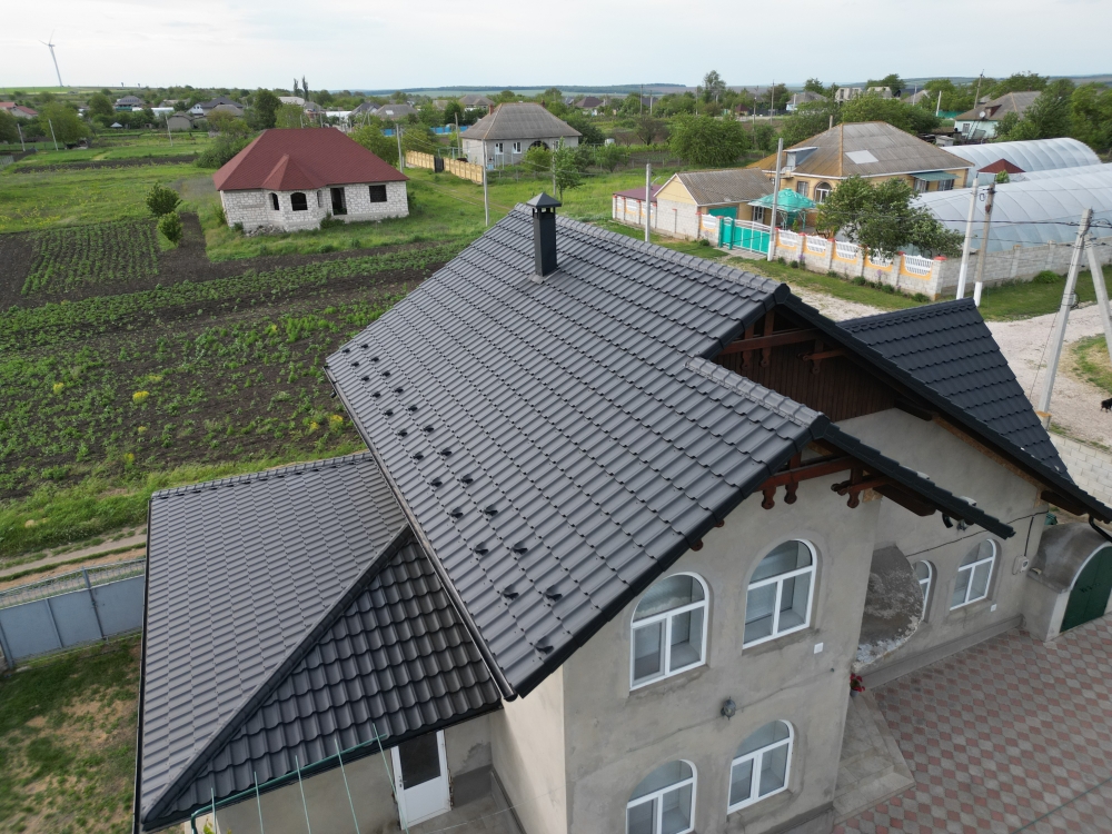 Частный дом с серой крышей из металлочерепицы и снегозадержателями в Молдове
